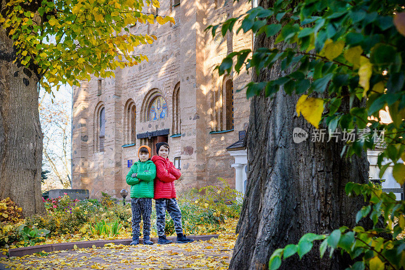 年轻的兄弟在一座古老的石头教堂附近。孩子们微笑着，哈哈