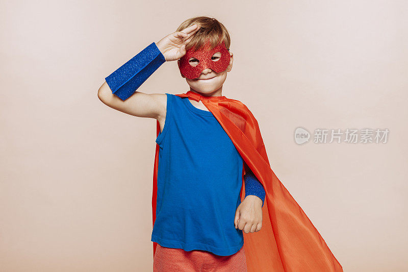 可爱的小超级英雄男孩在红色斗篷和面具