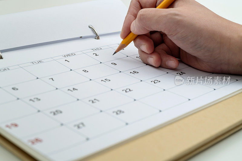 女人用铅笔在日历页上写字