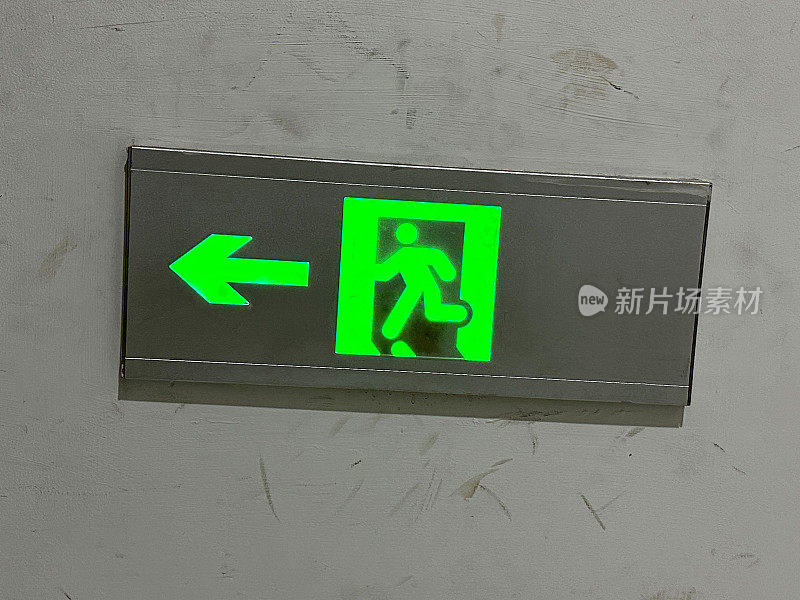 金属“消防出口”标志的特写图像，照明绿色消防出口墙安装的标志，重点在前景
