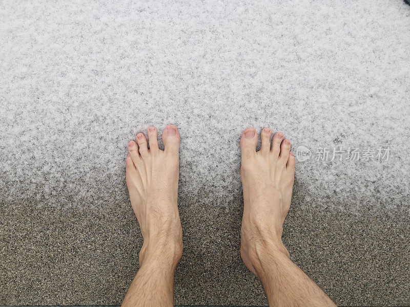 一个人的脚光着脚在地上过渡到雪