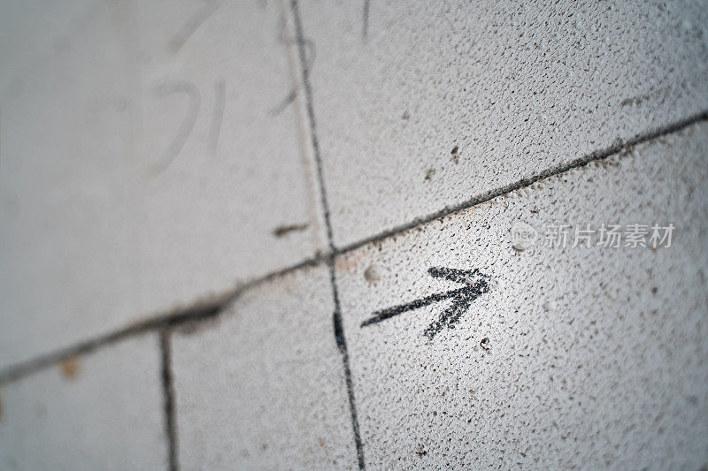 墙上的方向标记。在加气混凝土砖上从左到右画了一个黑色箭头。未经修补的光秃秃的墙壁上的尺寸标记