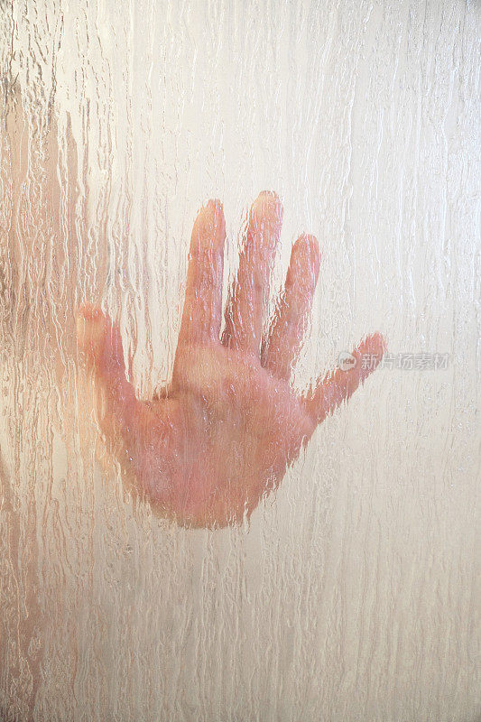 女人的手放在磨砂玻璃淋浴屏后面