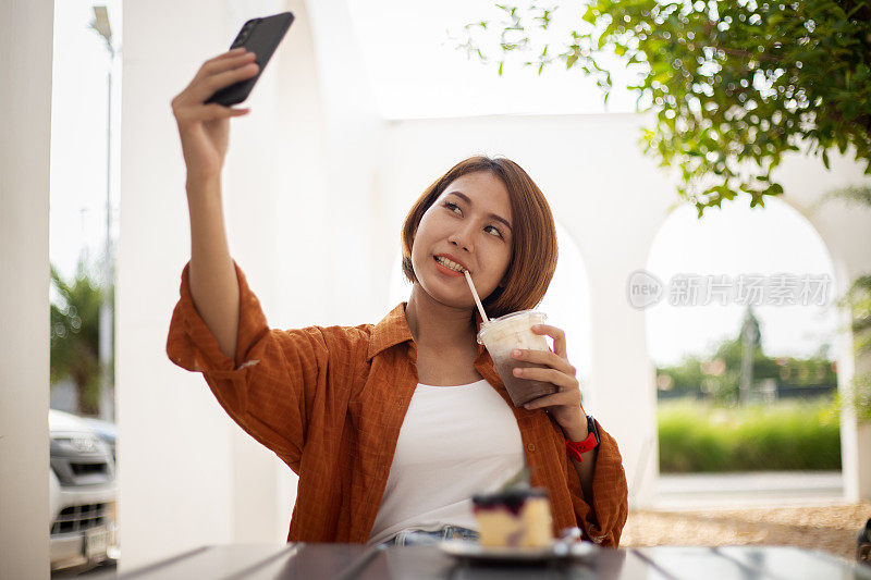 穿着黄衬衫的快乐女士坐在桌边喝着冰巧克力饮料。