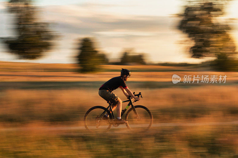日落时分，骑在沙砾自行车上的自行车手。动态模糊效果。