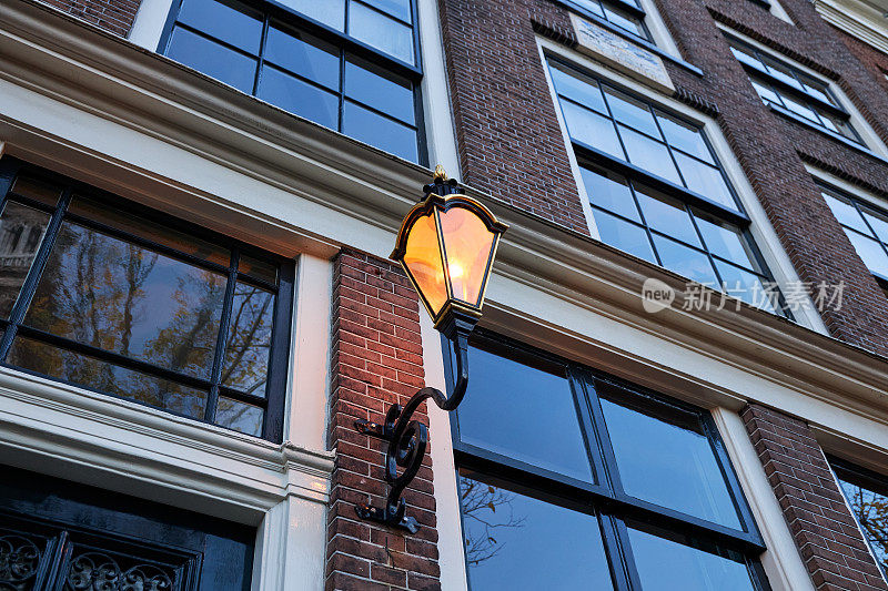 阿姆斯特丹历史悠久的运河房屋立面和黄昏时的街灯