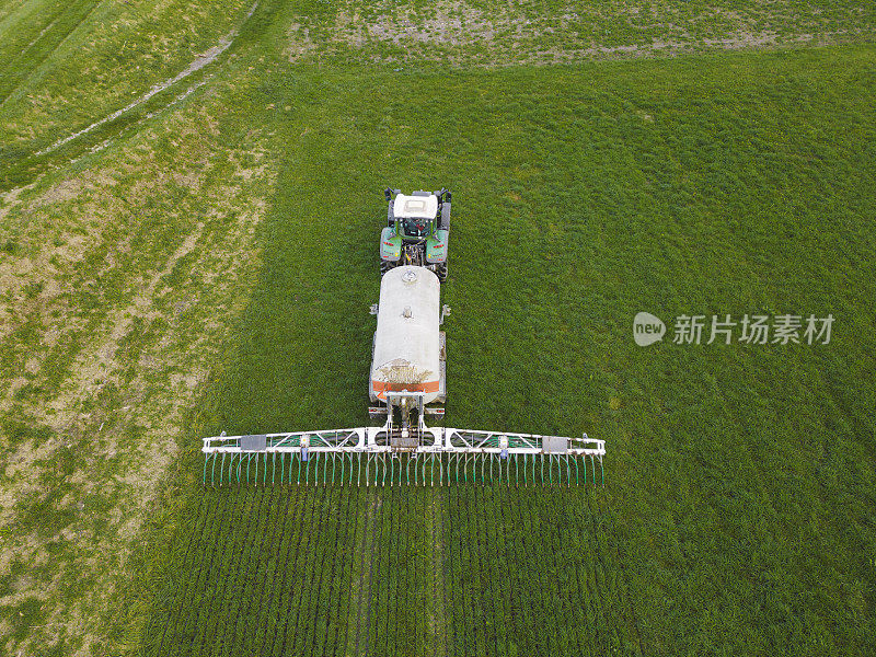 现代拖拉机在农田上工作的鸟瞰图，在草地上拖拉机犁地和播种的俯视图，农田耕作