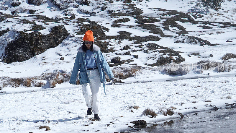 一个女人在寒冷的天气里穿行于白雪覆盖的山林之中