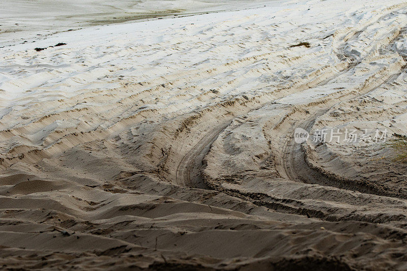 在沙滩上行驶的汽车留下的轮胎痕迹从泥土变成了白沙