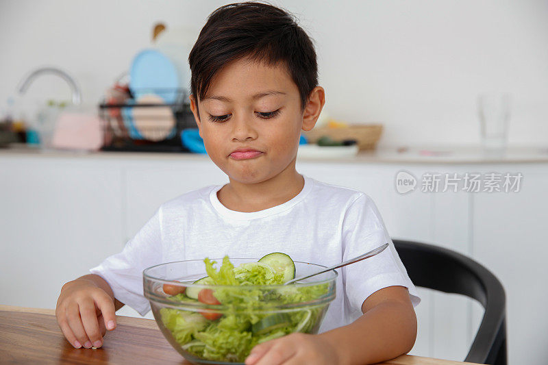 不快乐的小男孩不喜欢蔬菜沙拉