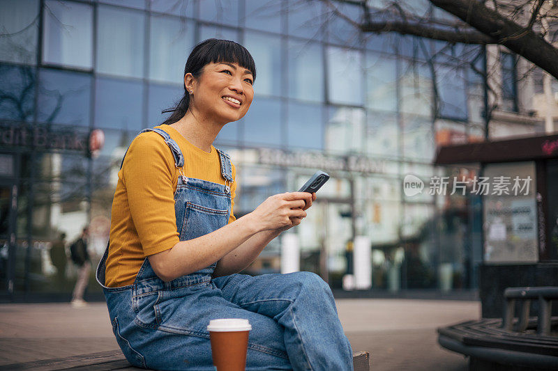 年轻女子在等公交车时玩手机