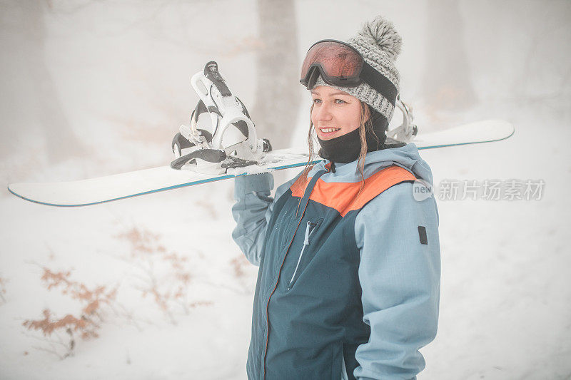 一个微笑的女滑雪板运动员准备在山上滑雪