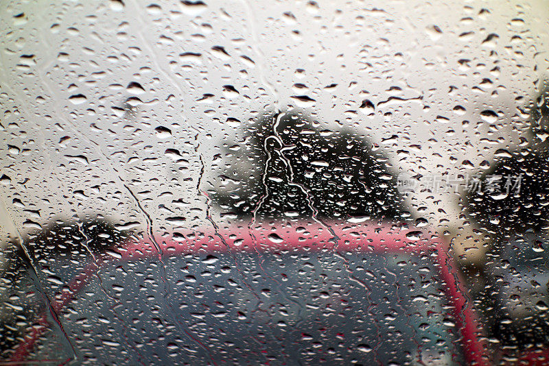 透过雨点覆盖的挡风玻璃看到的雨停车场