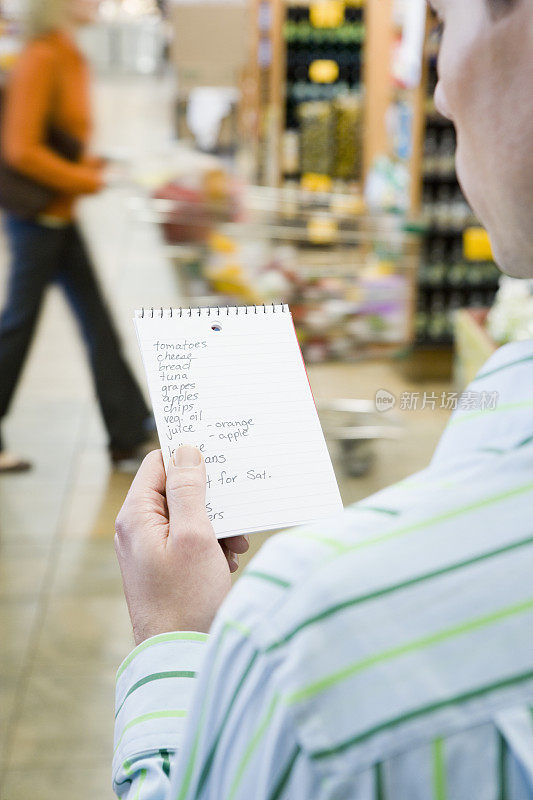 一名男子正在超市看购物清单