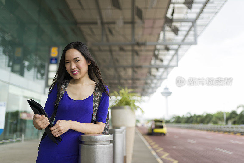 迷人的长发亚洲女人在机场候机厅外等候