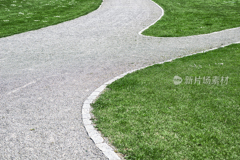 砾石小径穿过公园和绿色草地