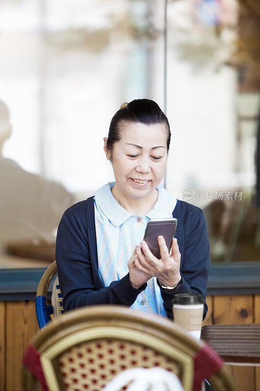 在路边咖啡馆外使用智能手机的快乐老人