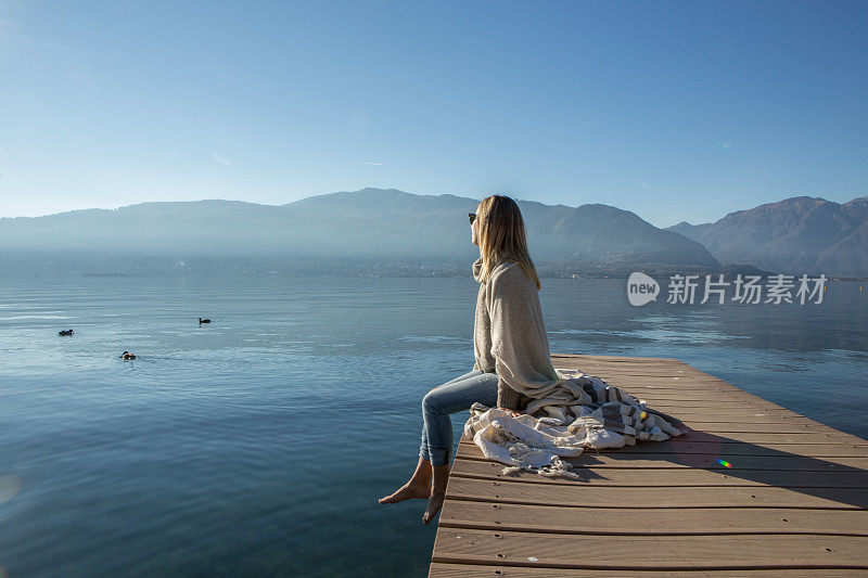 年轻女子在湖边码头上休息，看风景