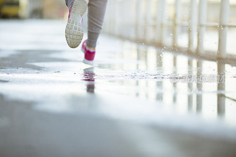 女人在雨天在沥青操场上跑步