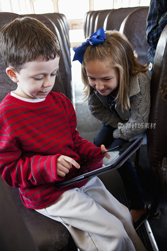 孩子们在校车上玩着平板电脑