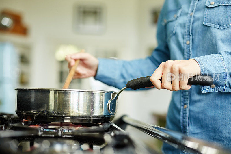 在煎锅里煮食物的女人的腹部