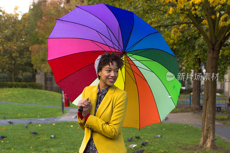 秋日里，在一把彩色大伞下的漂亮女人