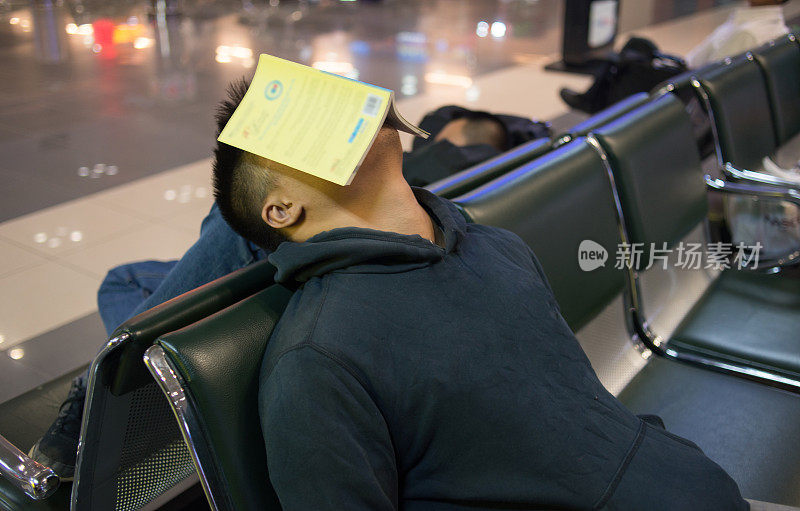 疲倦的人睡在机场的长凳上