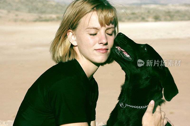 年轻女子与狗亲吻她的脸
