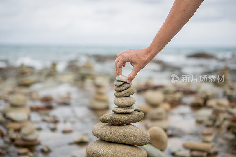 人们在海边的卵石塔上堆起最后一块石头