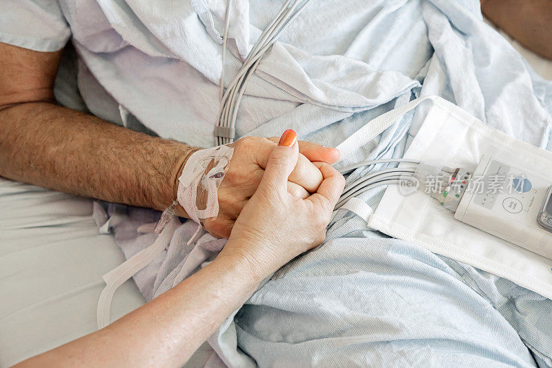 一个女人在医院里牵着她丈夫的手。