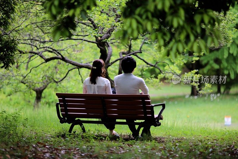 一对年轻夫妇在公园的长椅上享受春天