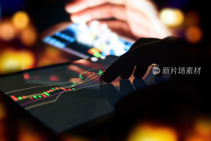 剪影手指在平板电脑与图形股票市场交易屏幕与抽象模糊智能手机散景背景，股票市场概念