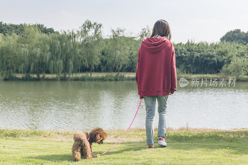 一个女人和她的小狗在湖边玩耍