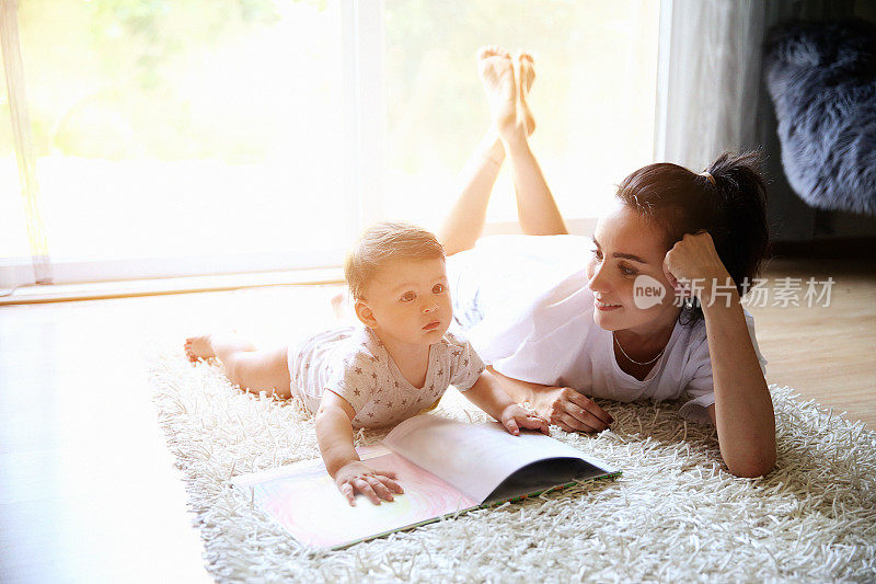 妈妈在地毯上给她的孩子读书