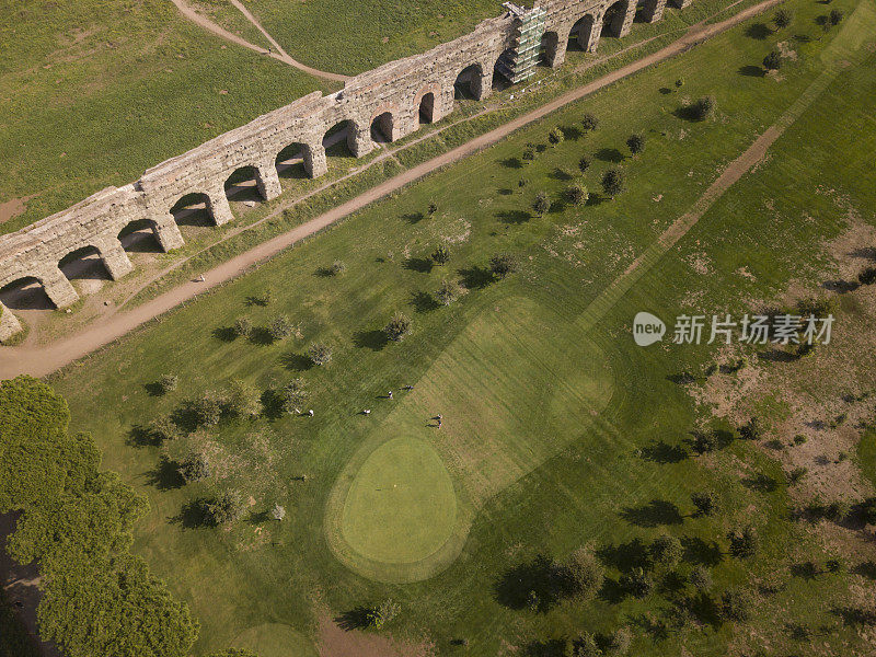 意大利罗马，一些人在古罗马渡槽附近的球场上打高尔夫的鸟瞰图。