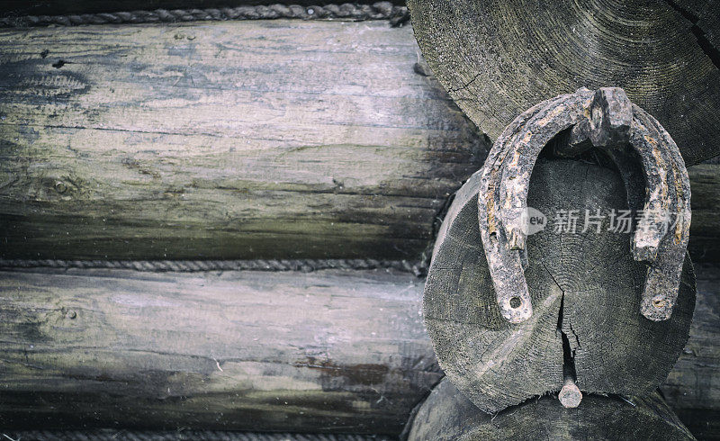 马蹄铁挂在一枚铁钉上，钉在木屋的墙上。人们的吉祥符号