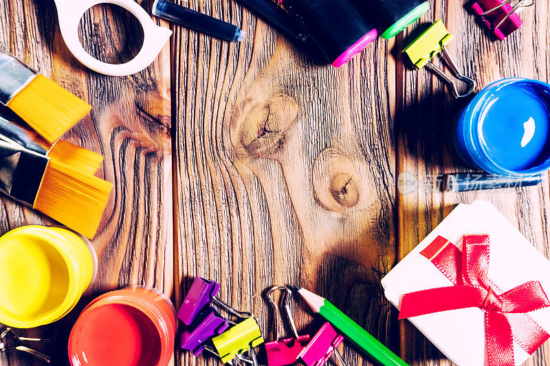 学校用品和礼品盒。回到学校。教育学校边界概念。艺术模板与复制空间。剪刀，画笔，丙烯酸颜料，回别针，钢笔墨水在木制背景上。
