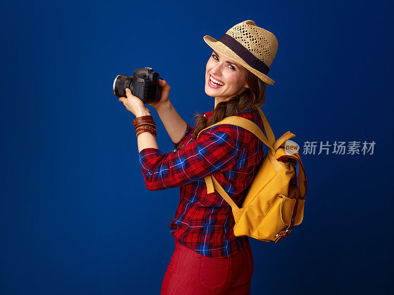微笑的年轻女子徒步旅行者与现代数码单反相机拍照