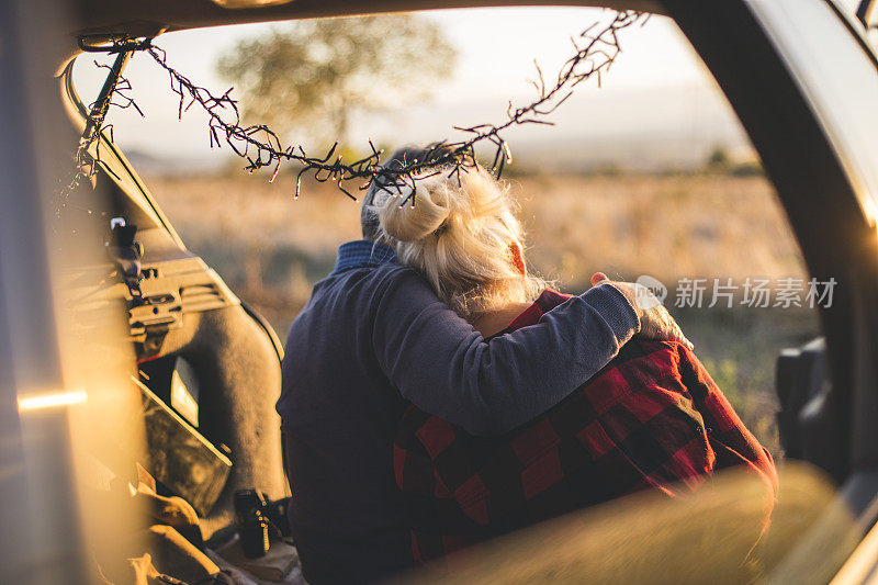 一对老年夫妇在徒步旅行前坐在敞篷汽车后备箱里