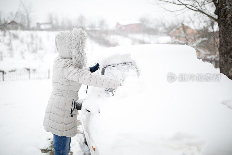 女人在清理被雪覆盖的汽车