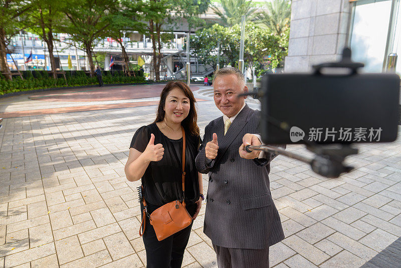 两个成熟的亚洲商人和成熟的亚洲女人享受泰国曼谷周围的生活