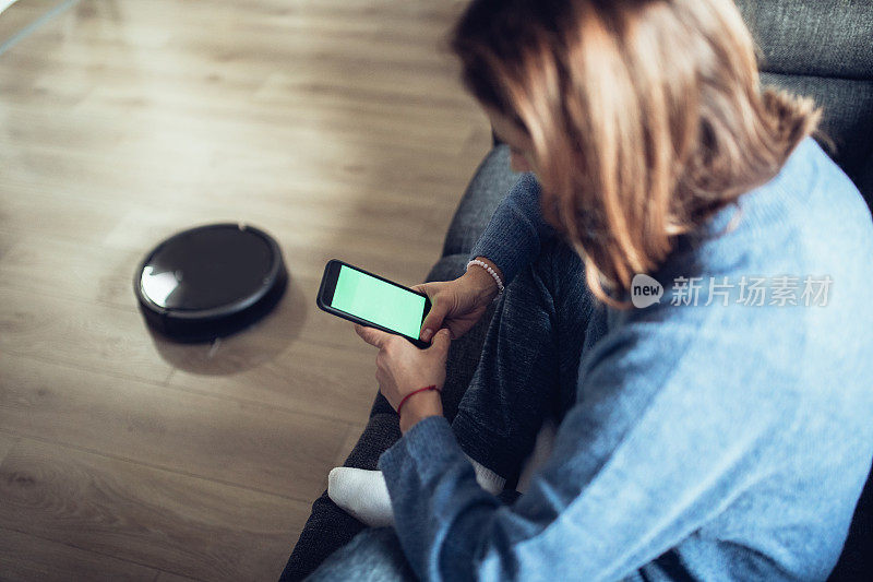 年轻女子使用家用机器人清洁应用程序