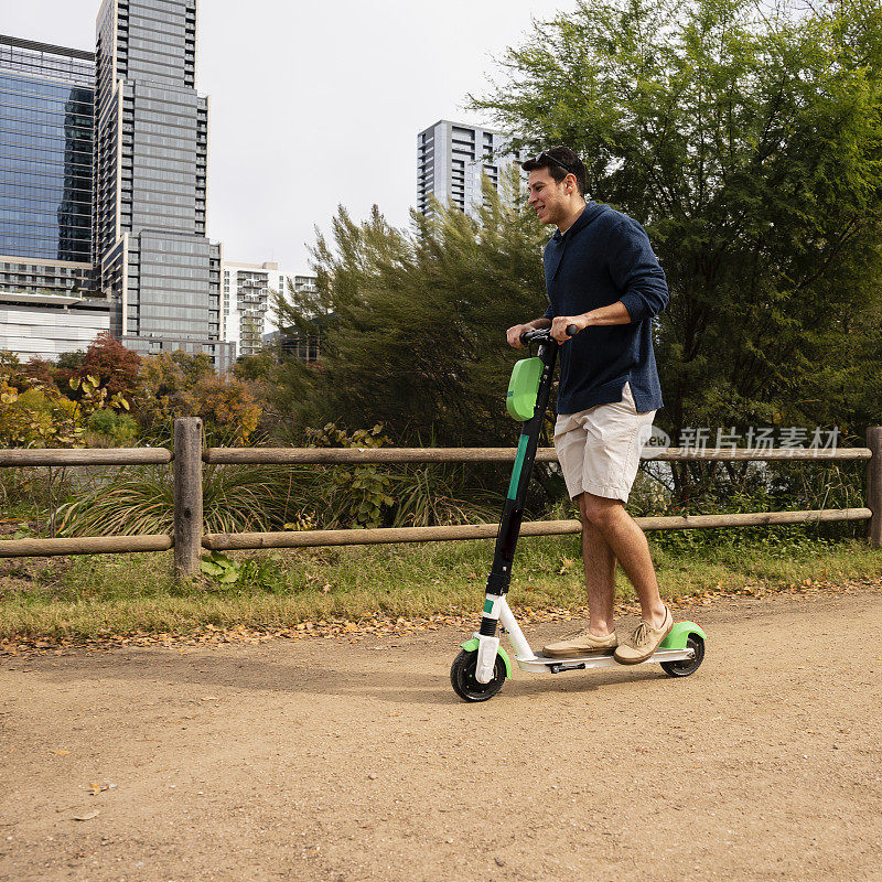 年轻快乐的西班牙人在公园里骑着租来的电动滑板车