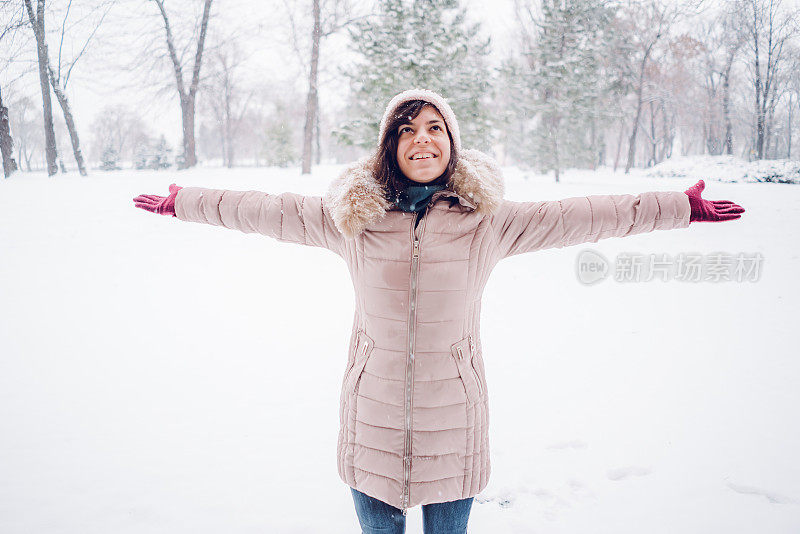 一个女人在白雪覆盖的公园里摊开双手