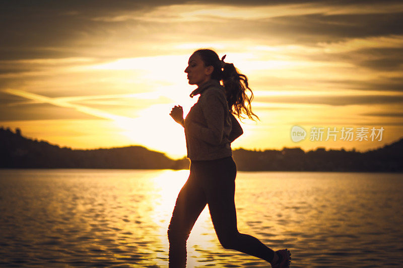 日落时分在海边跑步的女人