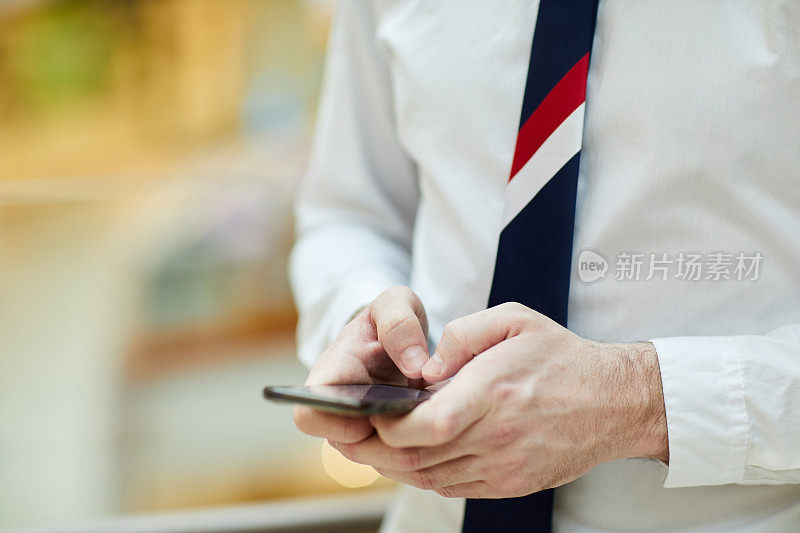 近距离特写:一位不知名的银行员工打着领带，穿着白衬衫，站在智能手机上做笔记