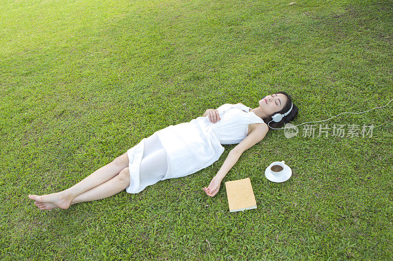 漂亮女人躺在草地上听音乐