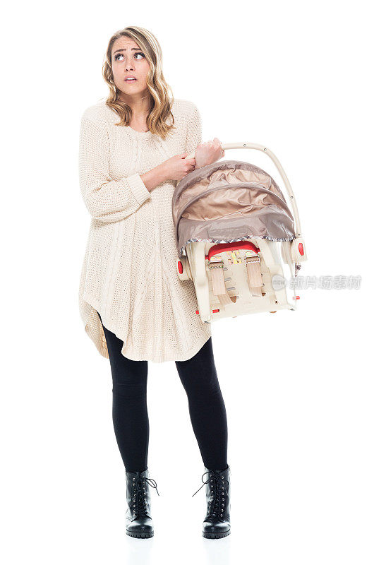 年轻漂亮的妈妈穿着毛衣抱着婴儿汽车座椅-困惑