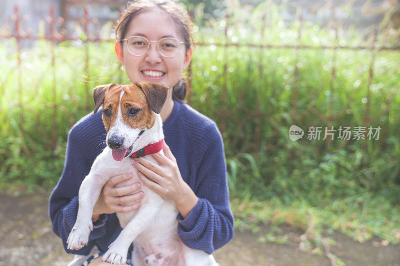 亚洲家庭十几岁的女孩玩好玩的她的宠物杰克罗素梗狗在花园在夏天的早晨