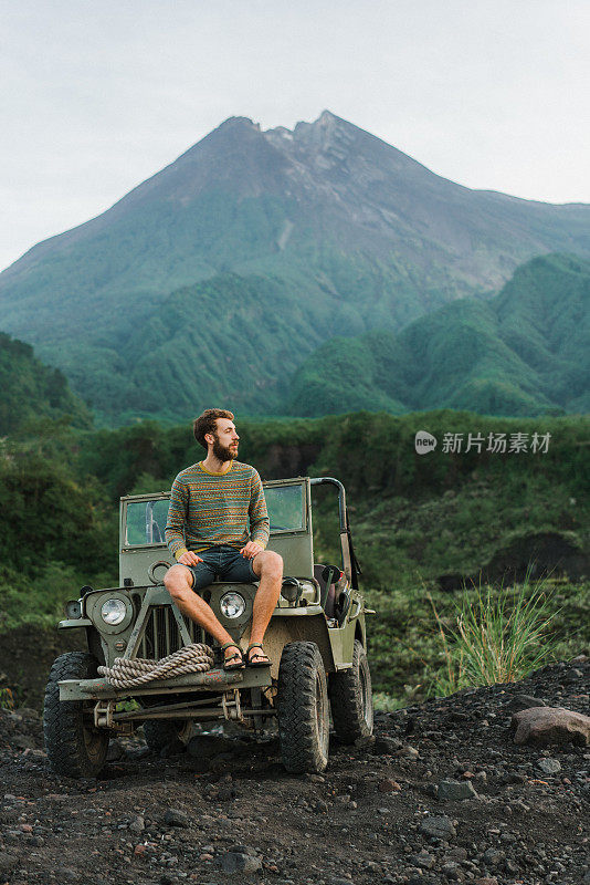 一名男子坐在老式SUV上，背景是默拉皮火山